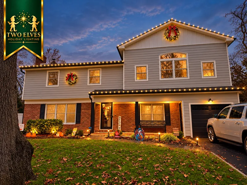 Two-story home at dusk with warm-white roofline lights and wreaths